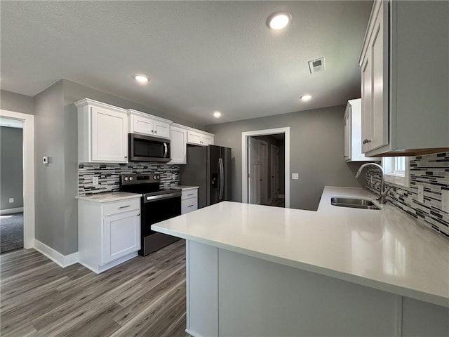 4909 S Creek Woods Dr, Saint Joseph, MO 64507 - kitchen with stainless steel appliances, decorative backsplash, a peninsula, light wood-type flooring, and light countertops