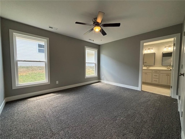 4909 S Creek Woods Dr, Saint Joseph, MO 64507 - unfurnished bedroom featuring light carpet, multiple windows, ensuite bathroom, and a ceiling fan