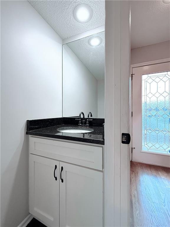 bathroom with a textured ceiling, hardwood / wood-style flooring, and vanity