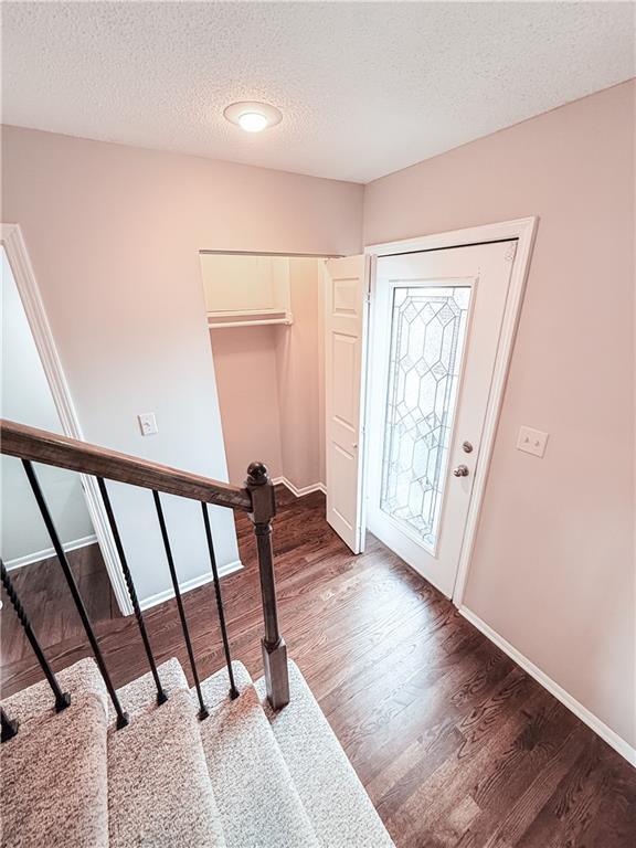 entryway with dark wood-type flooring and a textured ceiling