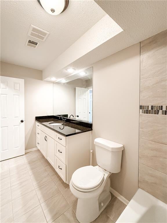 bathroom featuring toilet, vanity, tile patterned flooring, and a textured ceiling