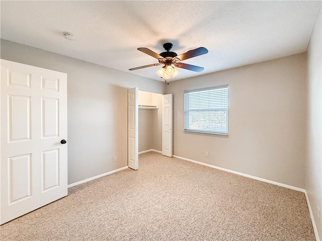 unfurnished bedroom featuring ceiling fan, a closet, a textured ceiling, and light colored carpet