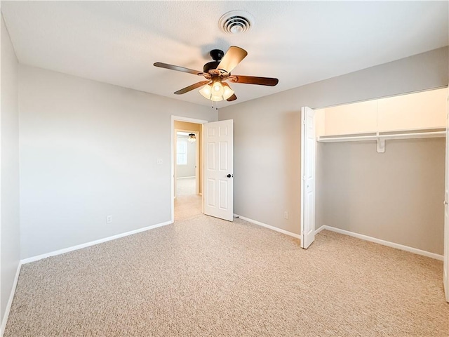 unfurnished bedroom with a closet, light colored carpet, and ceiling fan