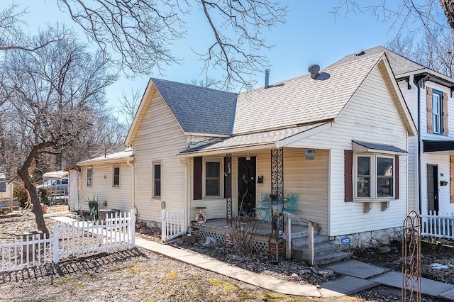 view of front facade featuring covered porch, a shingled roof, and fence