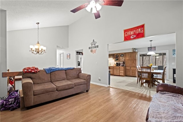 living room featuring high vaulted ceiling, ceiling fan with notable chandelier, and light wood-type flooring