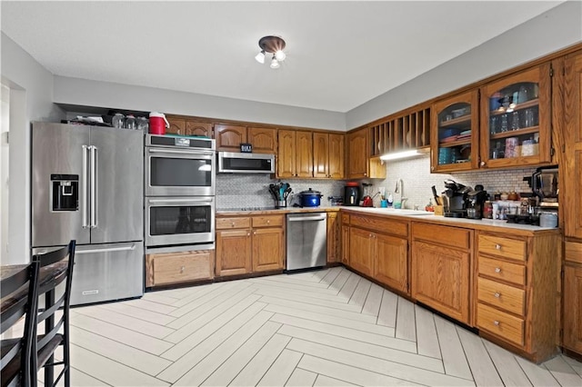 kitchen featuring appliances with stainless steel finishes, sink, light parquet floors, and backsplash