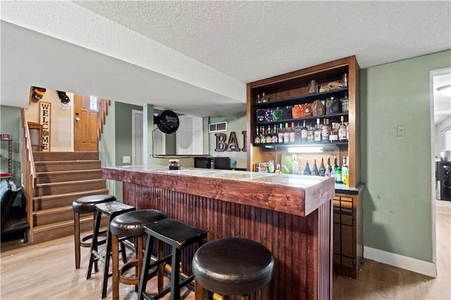 bar with hardwood / wood-style flooring and a textured ceiling