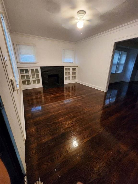 unfurnished living room with crown molding, a fireplace, dark hardwood / wood-style floors, and ceiling fan