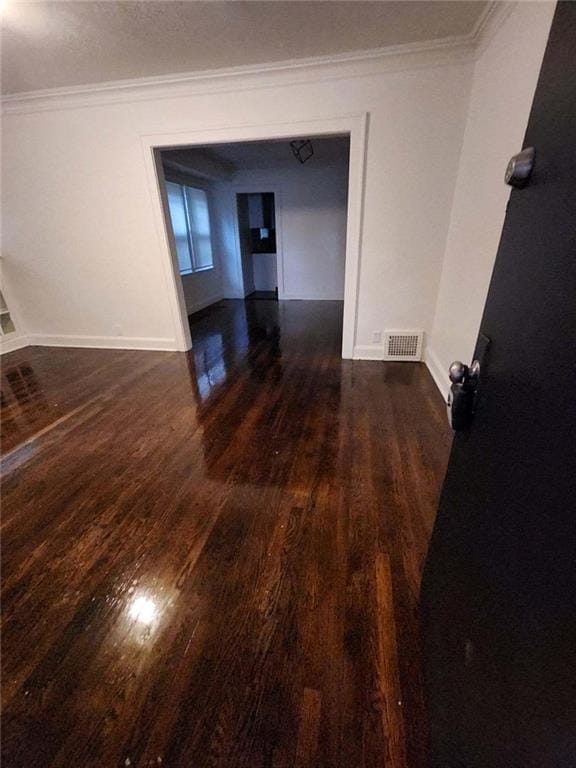 spare room with crown molding and dark wood-type flooring