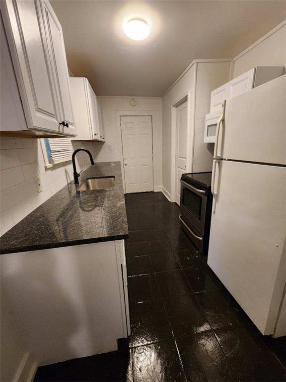 kitchen featuring sink, tasteful backsplash, dark stone countertops, white appliances, and white cabinets