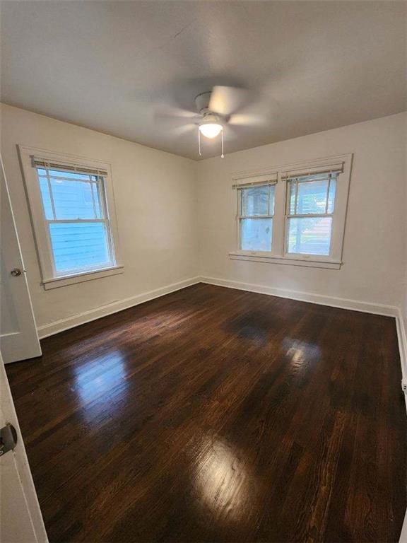 unfurnished room with a wealth of natural light, dark hardwood / wood-style floors, and ceiling fan