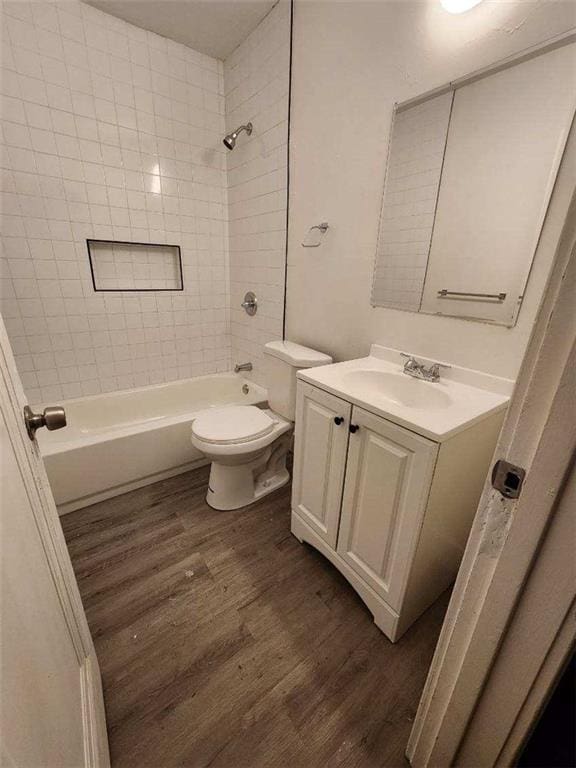 full bathroom with hardwood / wood-style flooring, vanity, toilet, and tiled shower / bath combo