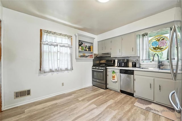 746 Salem Rd, Excelsior Springs, MO 64024 - kitchen with stainless steel appliances, light wood-style flooring, light countertops, backsplash, and under cabinet range hood