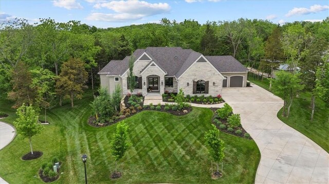 24982 W 106th Ct, Olathe, KS 66061 - french country home with stone siding, driveway, a front yard, and a forest view