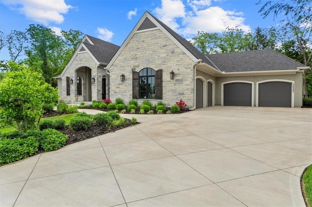 24982 W 106th Ct, Olathe, KS 66061 - french country home featuring an attached garage, stone siding, driveway, and stucco siding