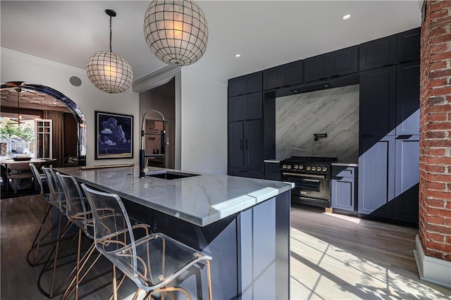 kitchen featuring light stone counters, a sink, wood finished floors, crown molding, and high end range