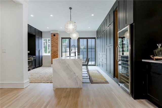 kitchen with dark cabinetry, decorative light fixtures, recessed lighting, and light wood finished floors