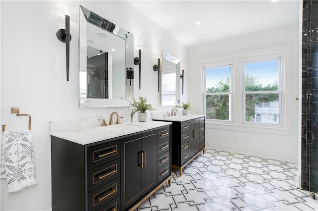 bathroom with walk in shower, two vanities, baseboards, and a sink