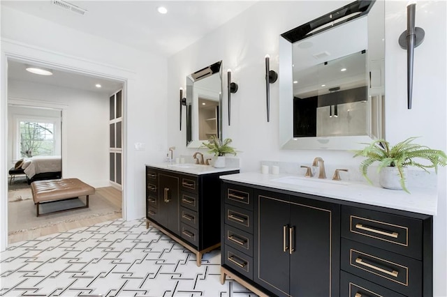 ensuite bathroom featuring two vanities, visible vents, connected bathroom, and a sink