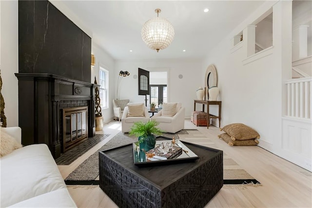 living area with light wood finished floors, a chandelier, recessed lighting, and a large fireplace