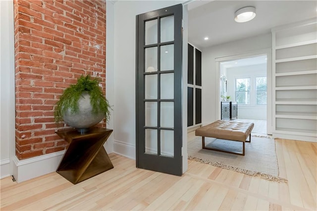 interior space featuring baseboards, wood finished floors, and brick wall