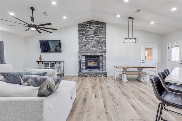 living room featuring vaulted ceiling, a fireplace, and light hardwood / wood-style floors