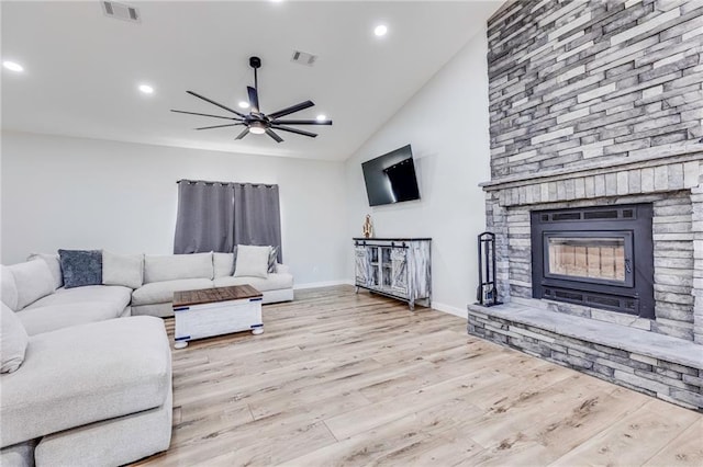 living room featuring high vaulted ceiling, a fireplace, ceiling fan, and light hardwood / wood-style flooring