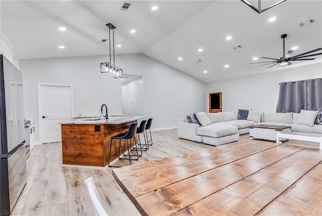 living room featuring ceiling fan, lofted ceiling, sink, and light hardwood / wood-style floors