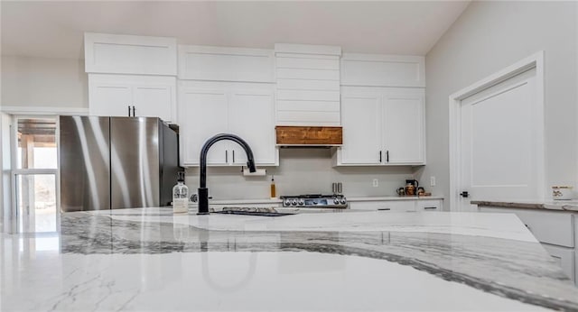 kitchen featuring stainless steel fridge, light stone countertops, and white cabinets