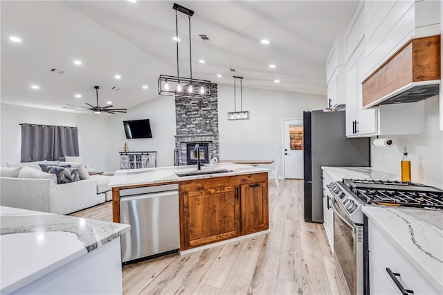 kitchen featuring pendant lighting, sink, white cabinetry, stainless steel appliances, and light stone counters