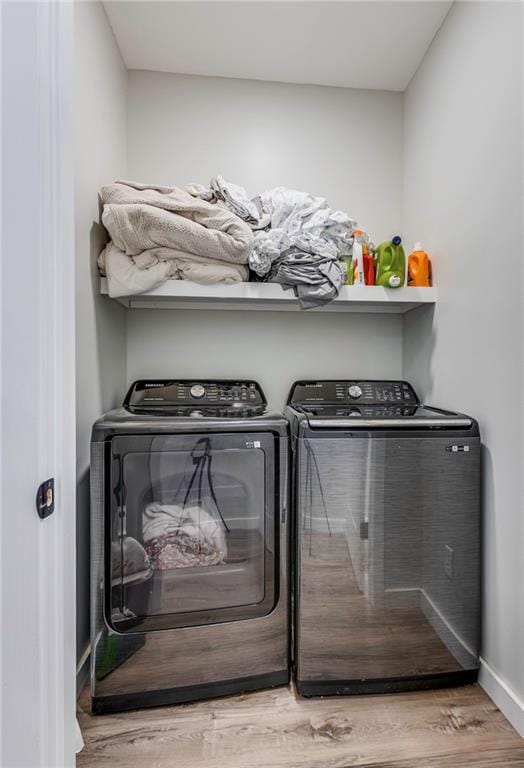 laundry room with washing machine and clothes dryer and hardwood / wood-style floors