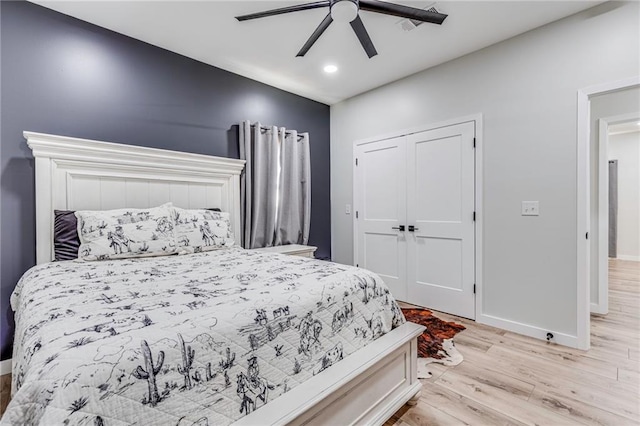 bedroom with ceiling fan, light wood-type flooring, and a closet