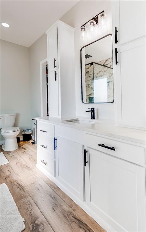 bathroom featuring vanity, toilet, a shower with shower door, and hardwood / wood-style floors