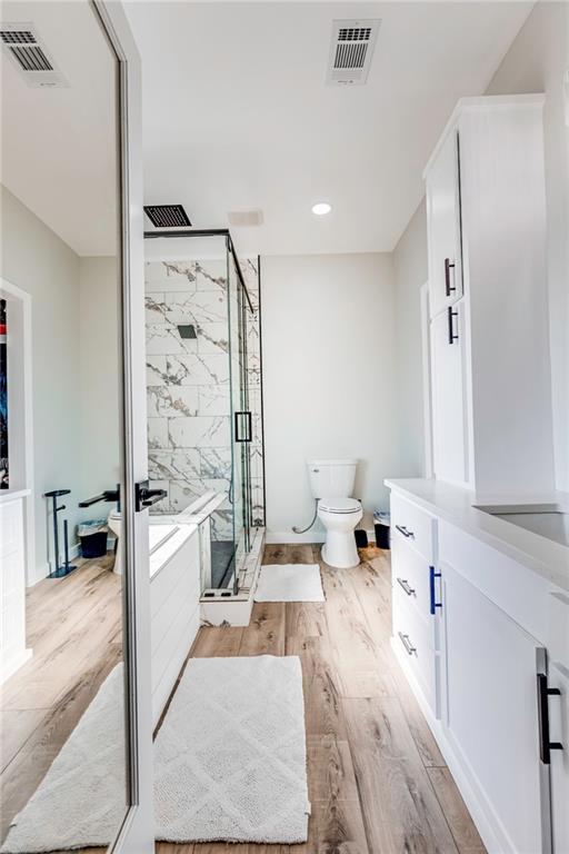 full bathroom featuring vanity, wood-type flooring, toilet, and separate shower and tub