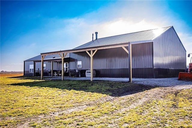 back of property featuring an outdoor structure and a yard