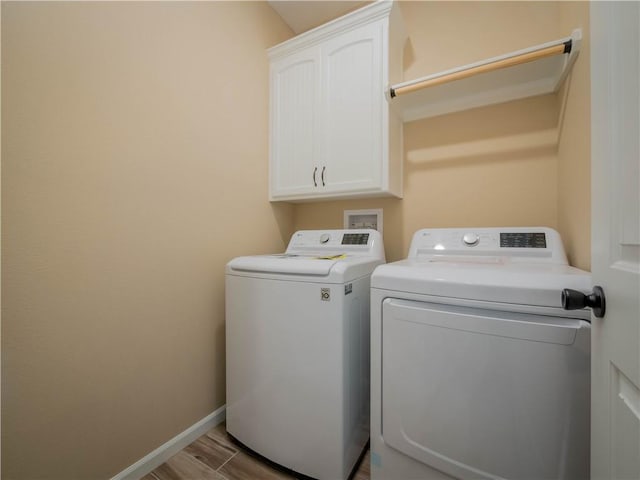 washroom featuring light hardwood / wood-style flooring, washer and clothes dryer, and cabinets