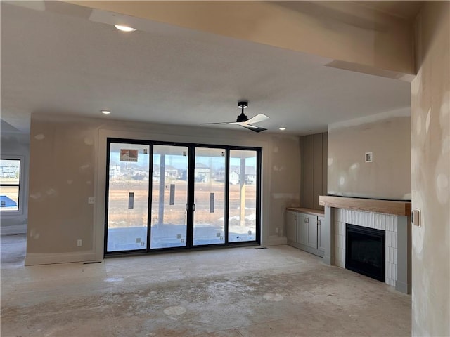 unfurnished living room featuring a tiled fireplace and ceiling fan