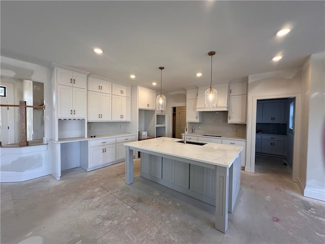 kitchen with sink, a center island with sink, white cabinets, and decorative light fixtures