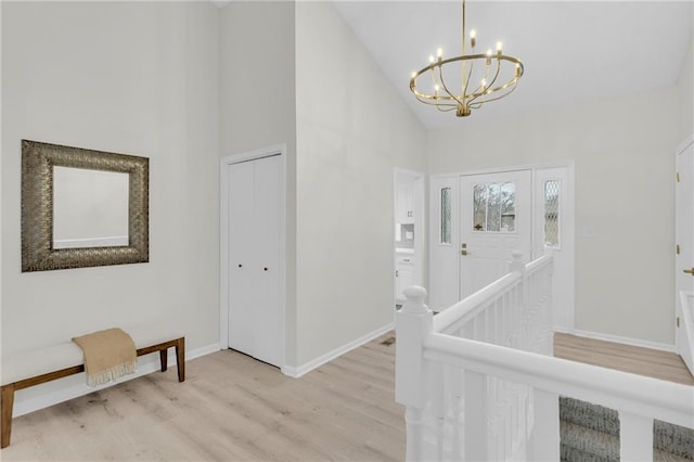 foyer entrance featuring a notable chandelier, light hardwood / wood-style flooring, and high vaulted ceiling