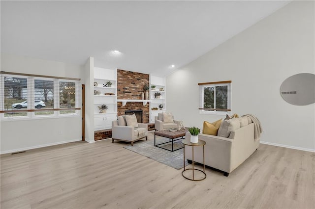 living room featuring built in shelves, a brick fireplace, high vaulted ceiling, and light hardwood / wood-style flooring