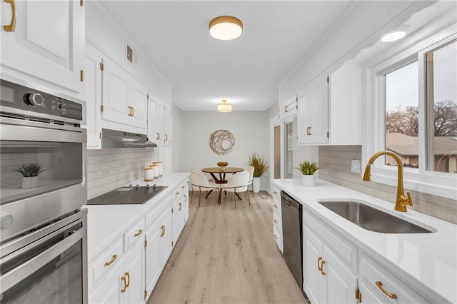 kitchen with tasteful backsplash, sink, white cabinets, light hardwood / wood-style floors, and black appliances