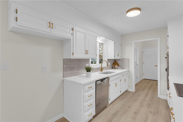 kitchen featuring sink, dishwasher, white cabinetry, light hardwood / wood-style floors, and decorative backsplash