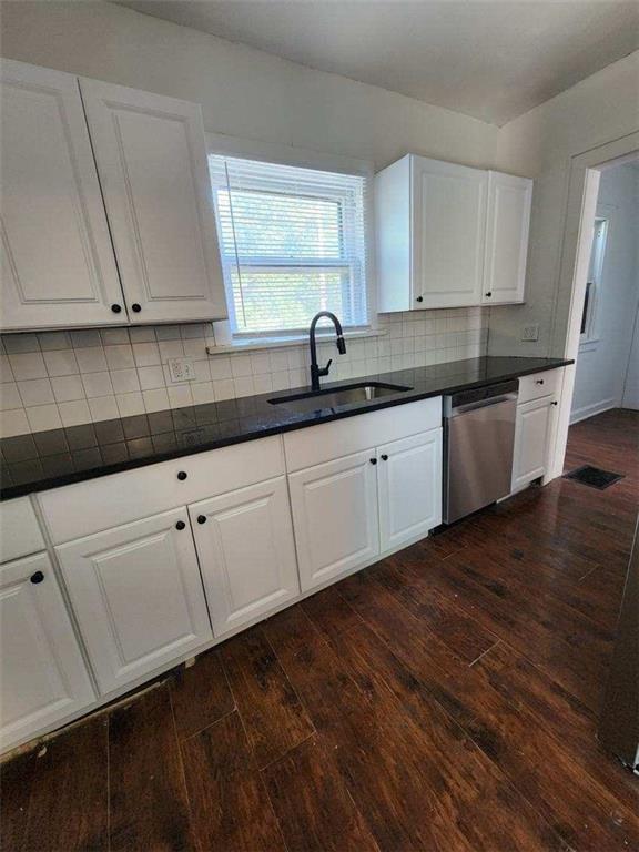 kitchen featuring white cabinetry, sink, backsplash, dark hardwood / wood-style flooring, and stainless steel dishwasher