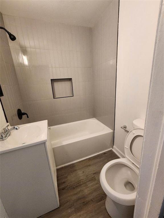 full bathroom featuring vanity, hardwood / wood-style floors, tiled shower / bath combo, and toilet