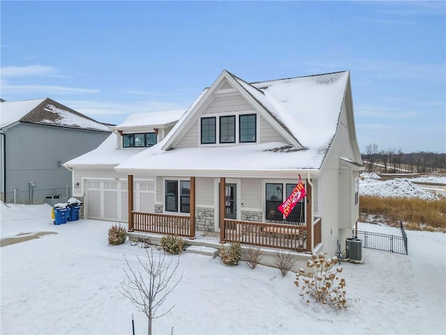 view of front of property featuring cooling unit, a garage, and covered porch