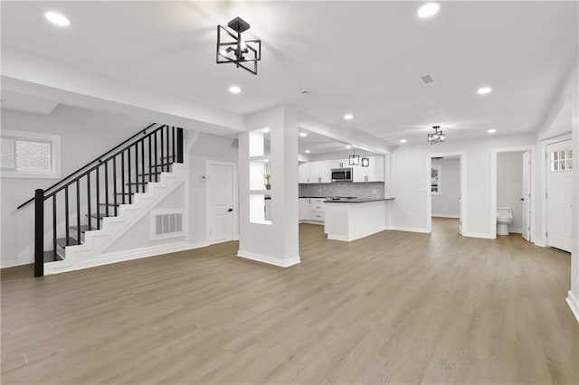 unfurnished living room featuring recessed lighting, visible vents, stairway, light wood-type flooring, and baseboards