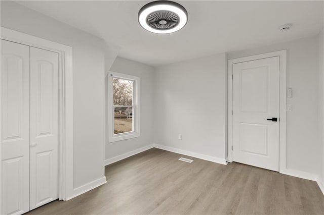 unfurnished bedroom with light wood-style floors, visible vents, and baseboards