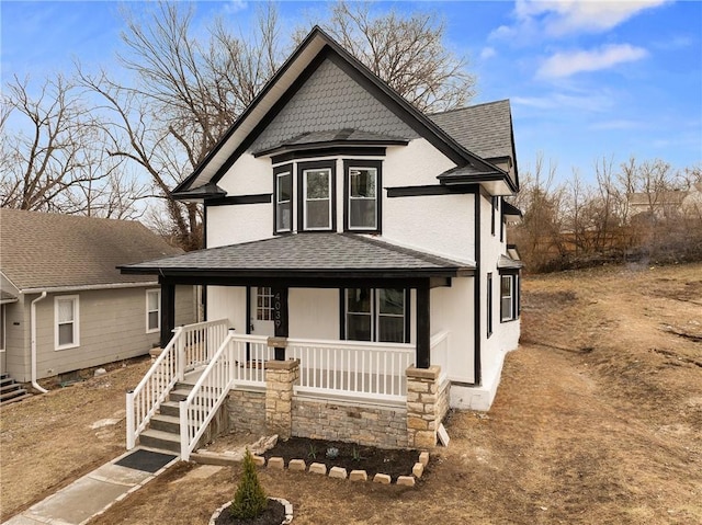 victorian home featuring covered porch and roof with shingles