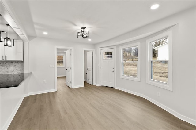 unfurnished dining area featuring recessed lighting, wood finished floors, an inviting chandelier, and baseboards