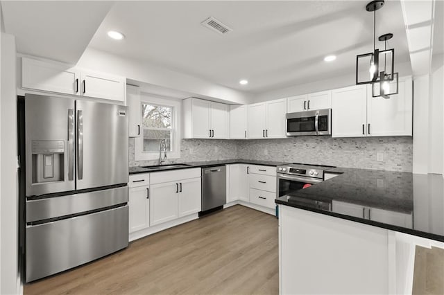 kitchen with light wood-style flooring, stainless steel appliances, a sink, visible vents, and white cabinetry